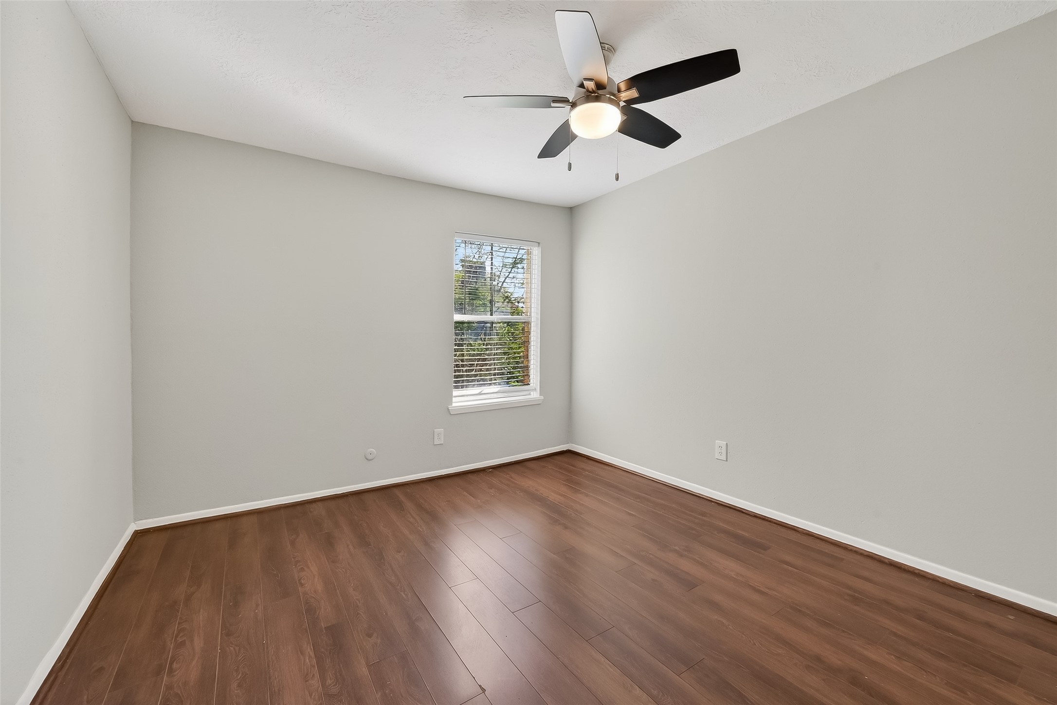 8646 Maplecrest Drive Houston, TX 77099 - Photo 26 of 36 an empty room with wooden floor ceiling fan and window