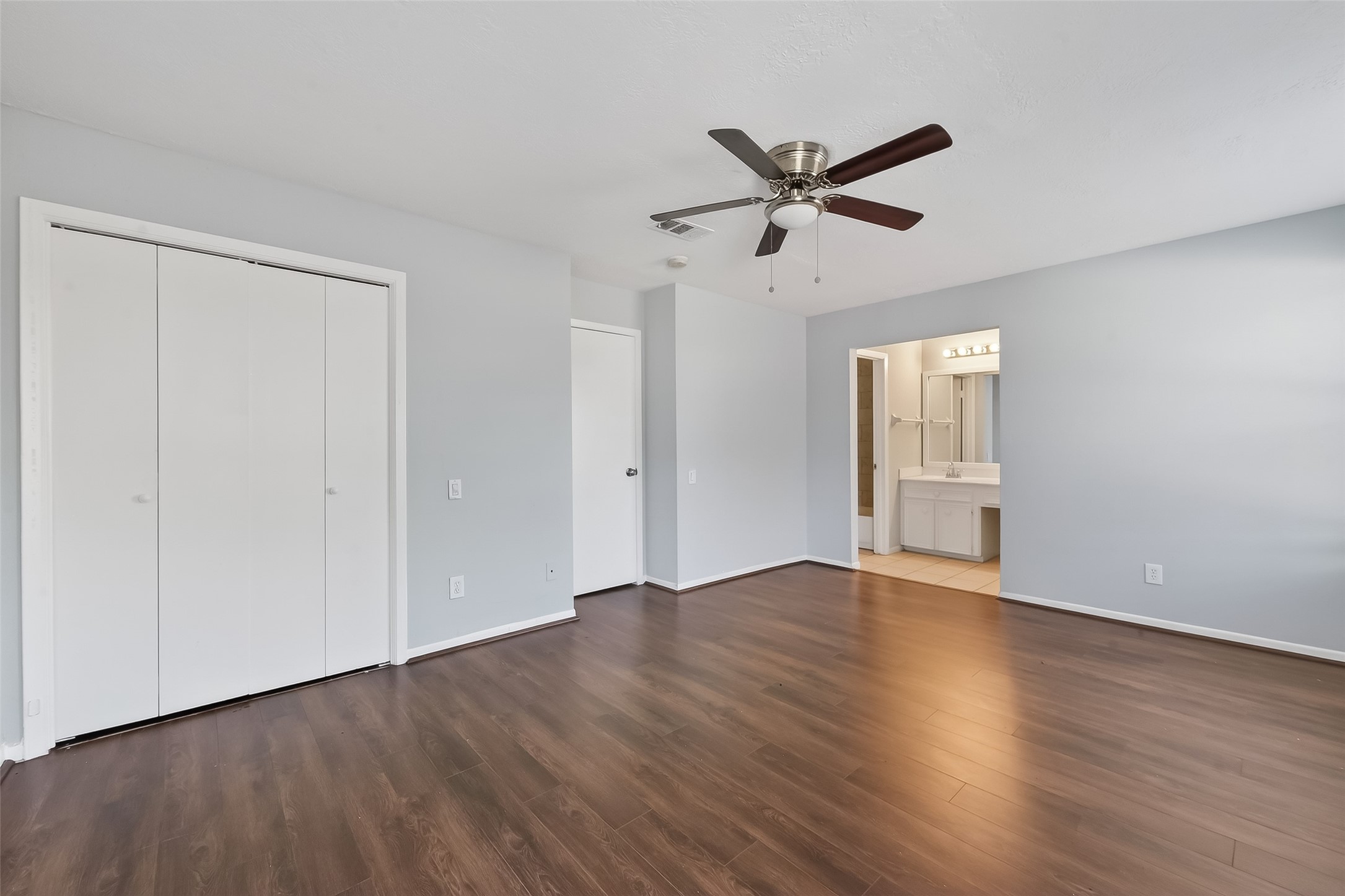 8646 Maplecrest Drive Houston, TX 77099 - Photo 29 of 36 an empty room with wooden floor a ceiling fan and windows