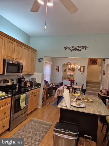 a view of a kitchen with kitchen island granite countertop a sink appliances and cabinets
