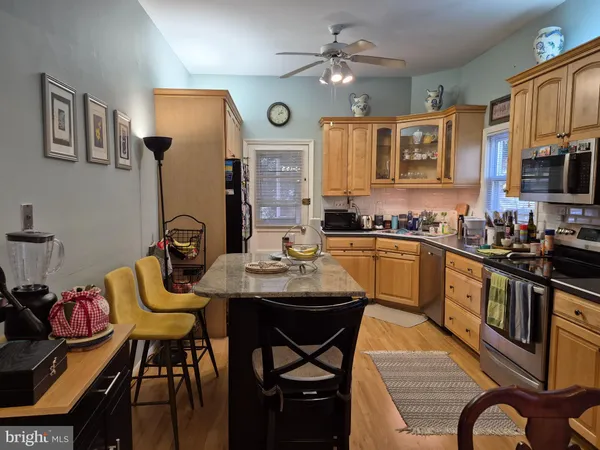 a kitchen with stainless steel appliances kitchen island granite countertop a sink a stove a dining table and chairs with wooden floor