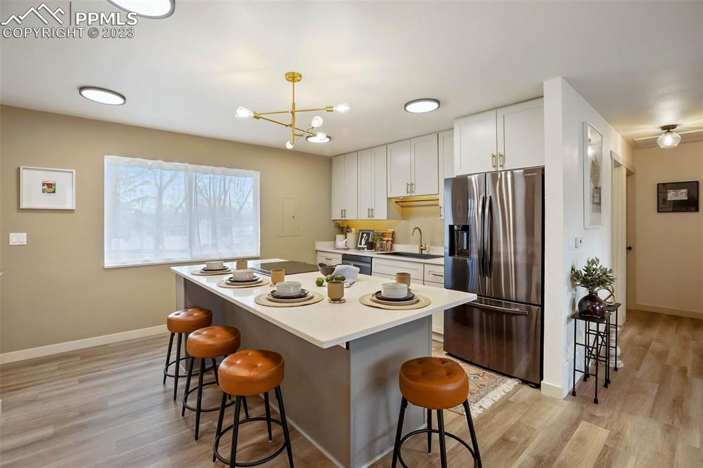 2415 Monterey Road Colorado Springs, CO 80910 - Photo 11 of 36 a kitchen with stainless steel appliances granite countertop a refrigerator a sink a stove a dining table and chairs with wooden floor