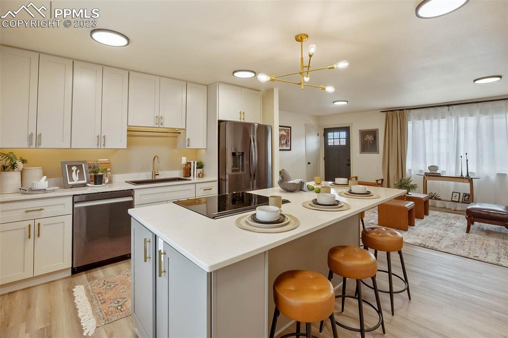 2415 Monterey Road Colorado Springs, CO 80910 - Photo 14 of 36 a kitchen with a sink a stove a refrigerator and white cabinets with wooden floor