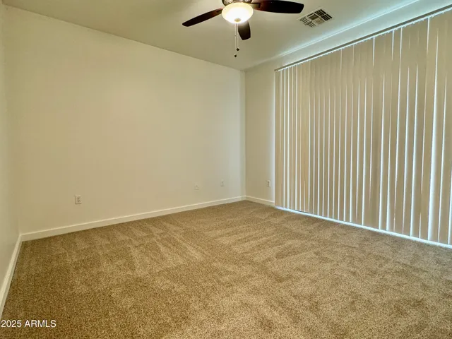 an empty room with a ceiling fan and carpet