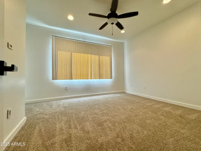 an empty room with a window and a ceiling fan