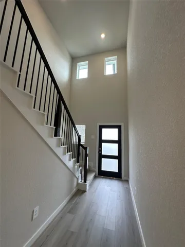 an empty room with wooden floor and a kitchen