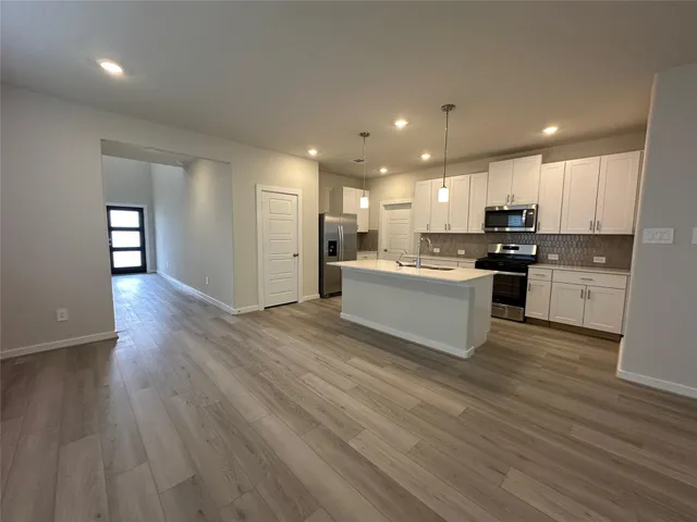 a large kitchen with kitchen island a sink dishwasher a stove and a refrigerator with wooden floor