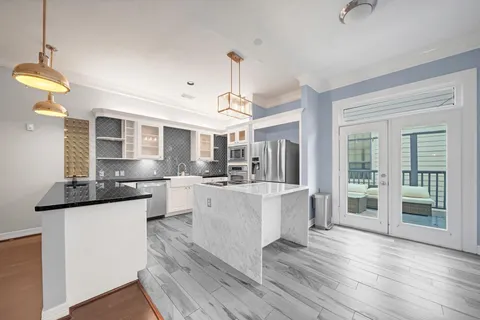 a large white kitchen with kitchen island a stove a sink dishwasher and white cabinets with wooden floor