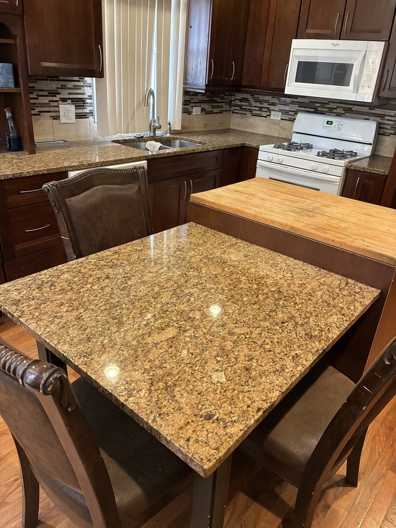 12346 South Indiana Avenue Chicago, IL 60628 - Photo 4 of 14 a kitchen with stainless steel appliances kitchen island granite countertop wooden cabinets a stove top oven and a sink