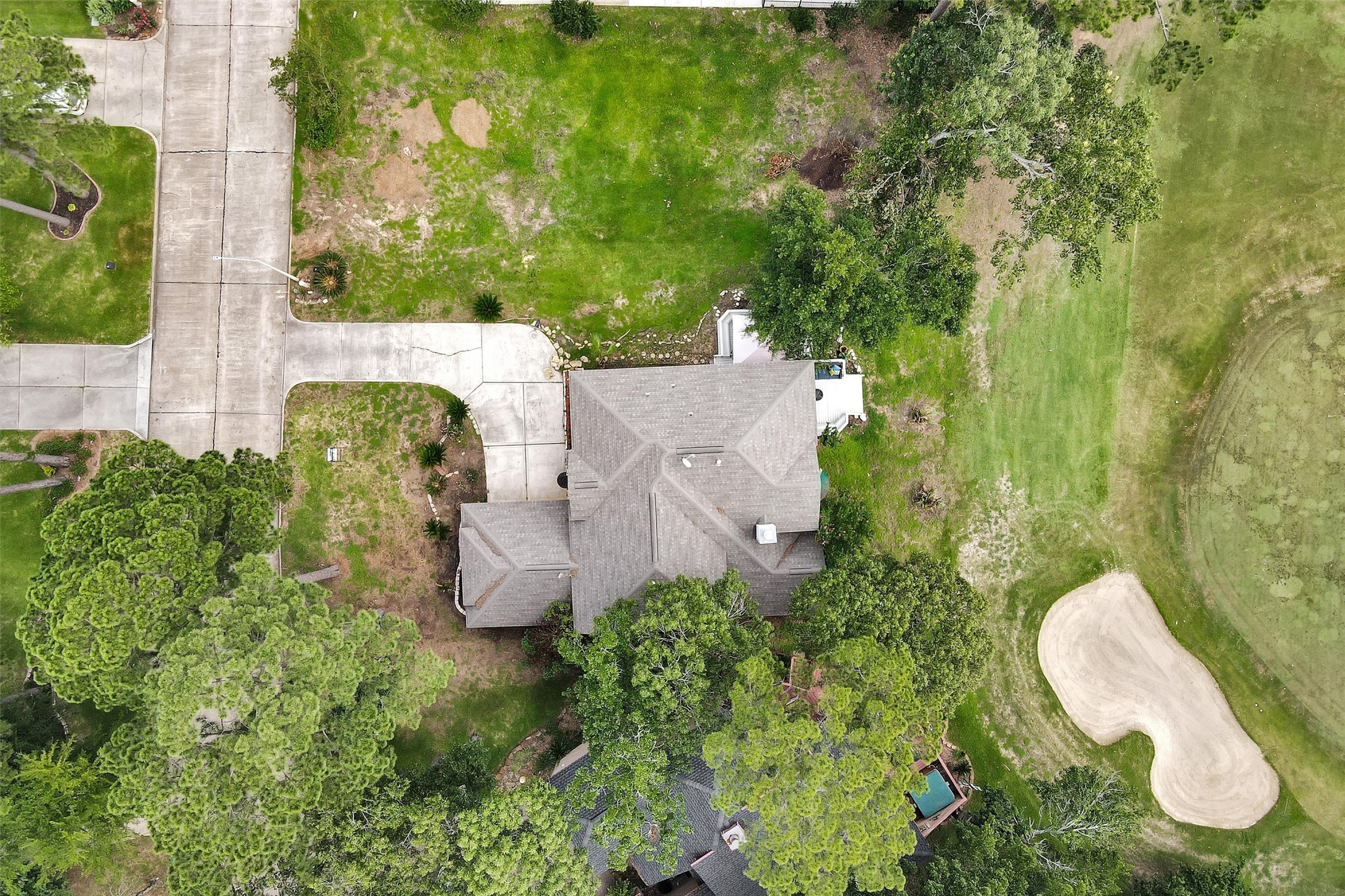 23 Alba Road Montgomery, TX 77356 - Photo 34 of 37 This aerial view shows a spacious home with a well-maintained yard, nestled among mature trees. The property is adjacent to a golf course, offering scenic views and direct access. The neighborhood has wide streets and a welcoming atmosphere.