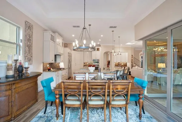 a kitchen with stainless steel appliances kitchen island granite countertop a stove a sink a refrigerator and a dining table with wooden floor