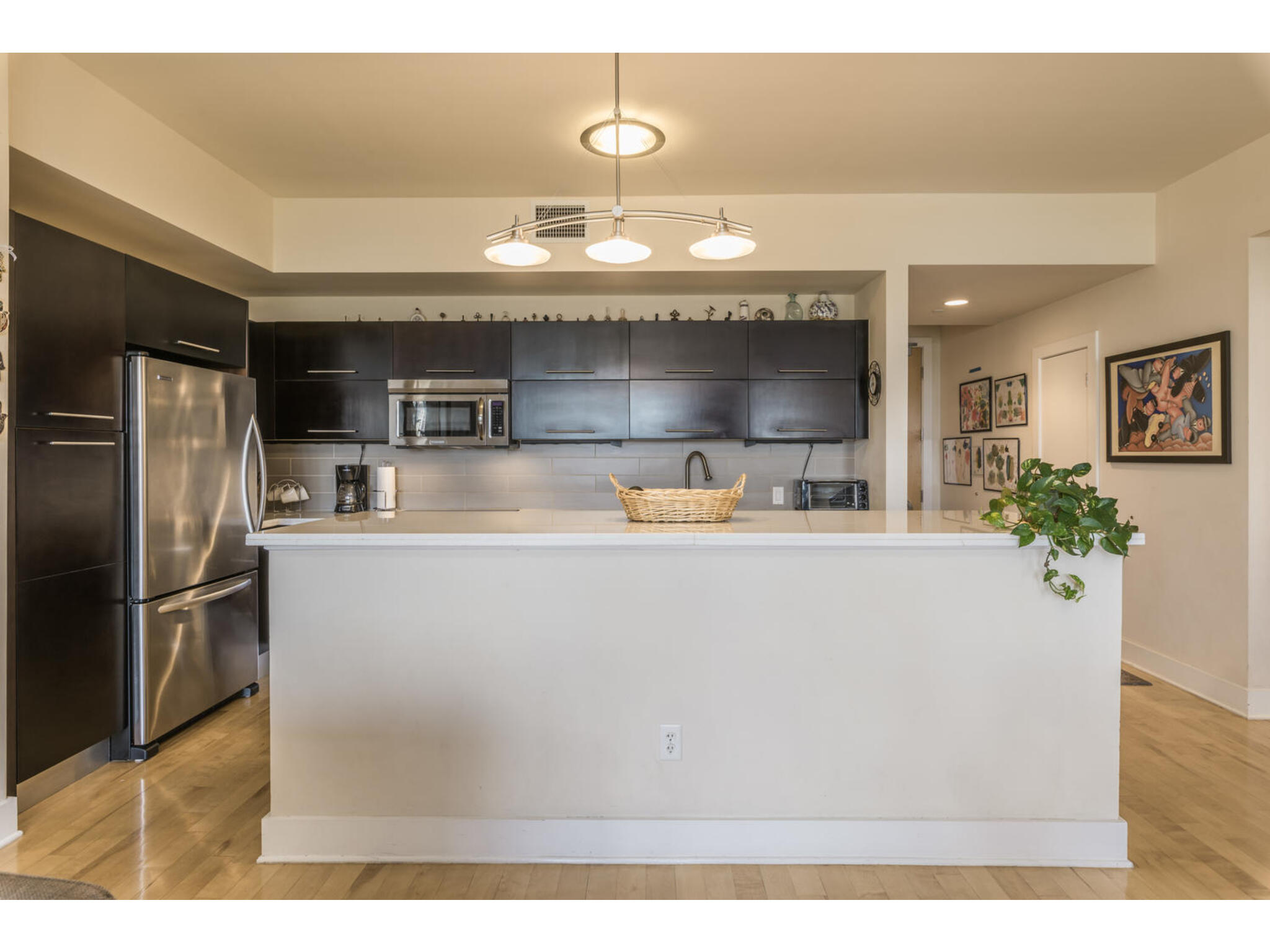 603 Davis Street, Unit 902 Austin, TX 78701 - Photo 10 of 21 Kitchen with stainless steel appliances, light countertops, hanging light fixtures, decorative backsplash, and a center island
