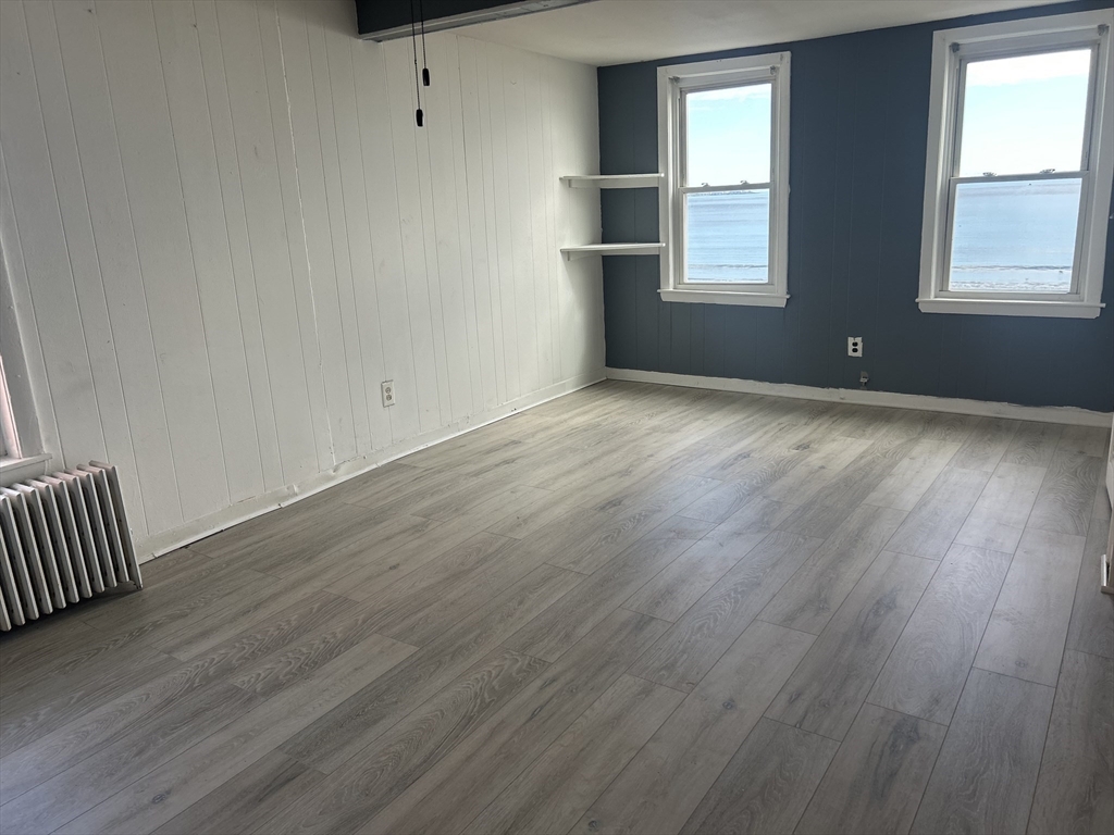 332 Revere Beach Boulevard, Unit 7 Revere, MA 02151 - Photo 5 of 8 an empty room with wooden floor and windows