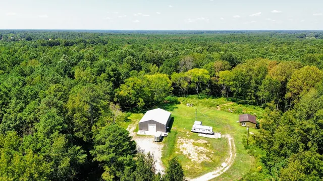 an aerial view of residential house with outdoor space and trees all around