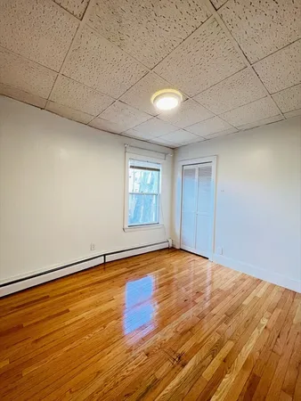 a view of an empty room with window and wooden floor