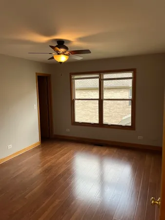 an empty room with wooden floor chandelier fan and windows