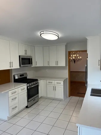 a kitchen with white cabinets appliances and sink