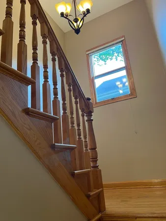 a view of staircase with railing and a chandelier
