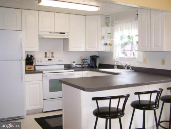 4005 Rustico Road Middle River, MD 21220 - Photo 5 of 20 a kitchen with stainless steel appliances a white table chairs and a refrigerator