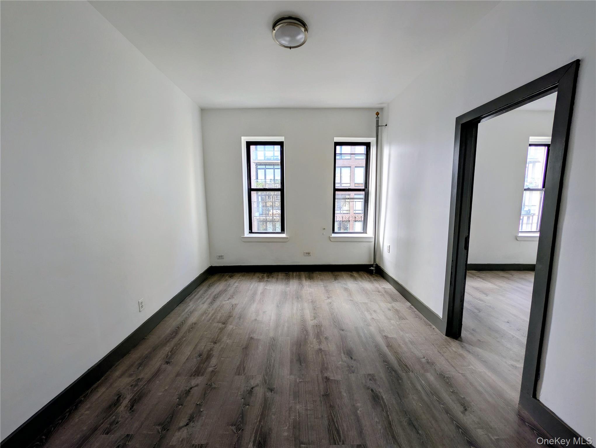 149 South 4th Street, Unit 25 Brooklyn, NY 11211 - Photo 4 of 12 an empty room with wooden floor and windows