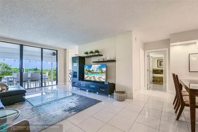 a living room with furniture a flat screen tv and a floor to ceiling window
