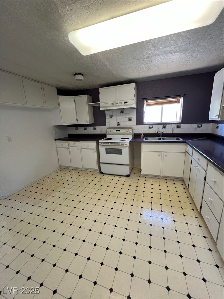 2151 West Simkins Road Pahrump, NV 89060 - Photo 14 of 23 Kitchen with light floors, dark countertops, electric stove, decorative backsplash, and a textured ceiling