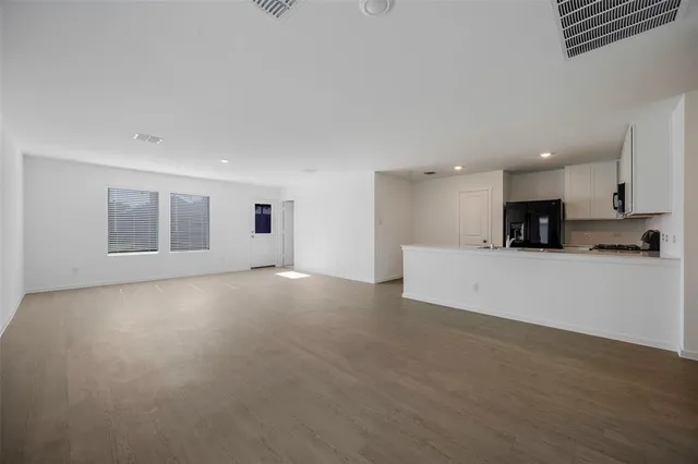 a view of a big room with wooden floor and windows