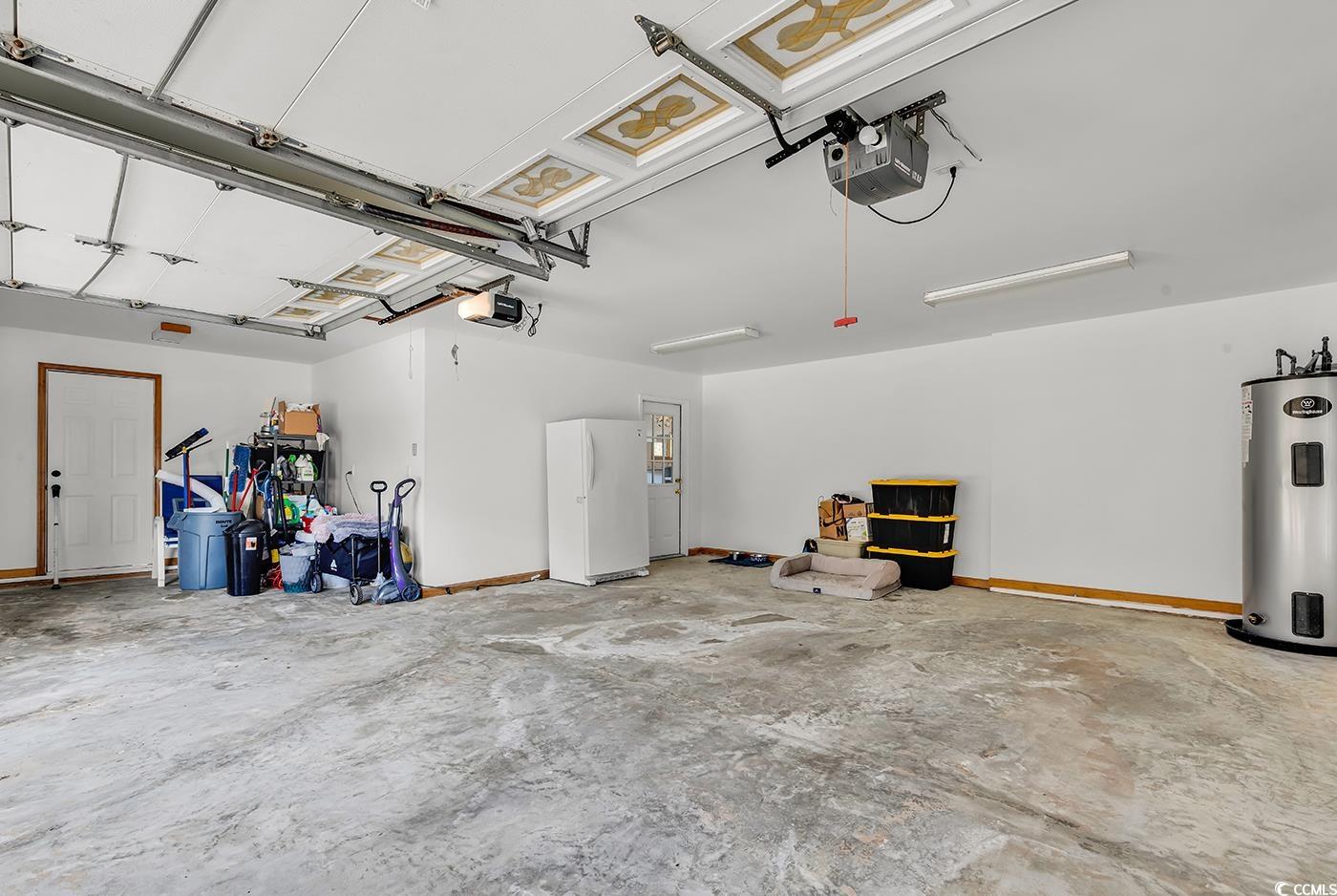 5938 Rahnavard Boulevard Myrtle Beach, SC 29588 - Photo 30 of 39 Garage with white fridge, a garage door opener, an