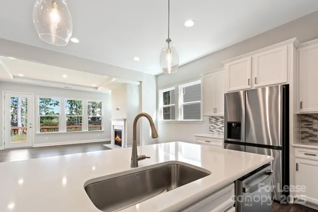 a kitchen with a refrigerator a sink and a stove with wooden floor
