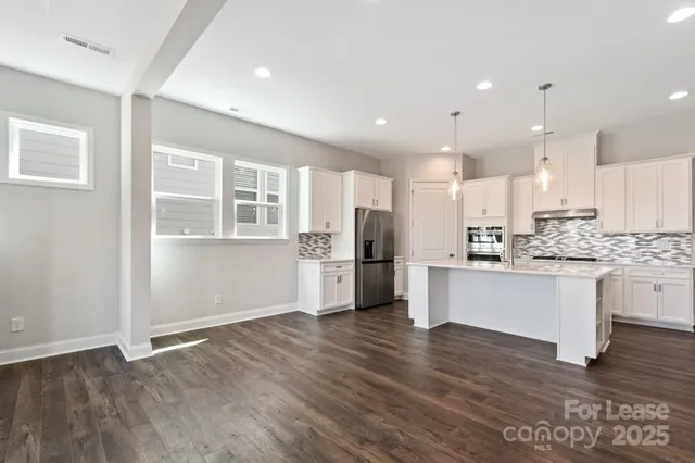 a kitchen with a refrigerator and white cabinets