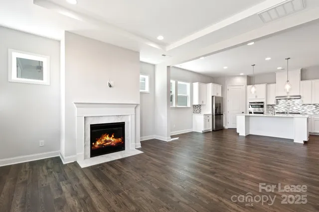 a view of an empty room with wooden floor and a fireplace