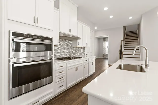 a kitchen with granite countertop white cabinets stainless steel appliances and sink