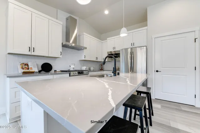 a kitchen with stainless steel appliances a sink a stove a refrigerator and cabinets