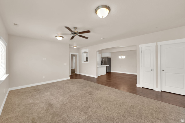 1823 North Crest Road Saratoga Springs, UT 84045 - Photo 6 of 18 Unfurnished living room featuring dark carpet, ceiling fan, and arched walkways
