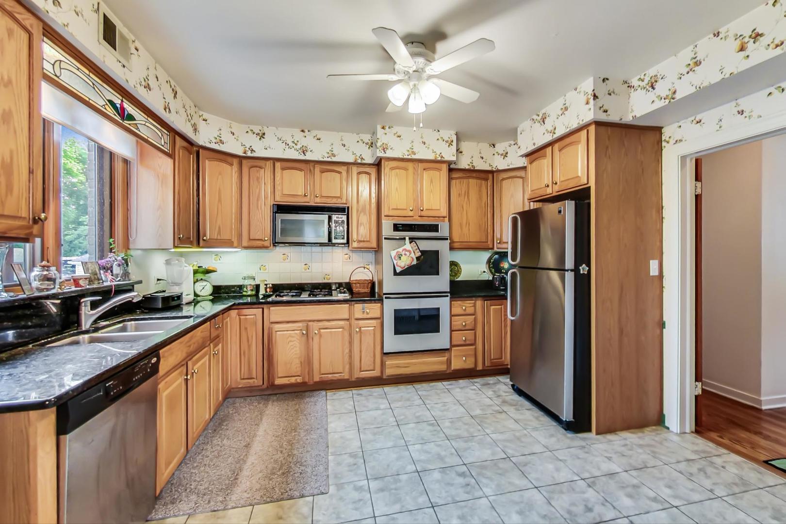 701 South Seminary Avenue Park Ridge, IL 60068 - Photo 14 of 60 a large kitchen with stainless steel appliances granite countertop a refrigerator a sink dishwasher a stove with wooden cabinets and floor