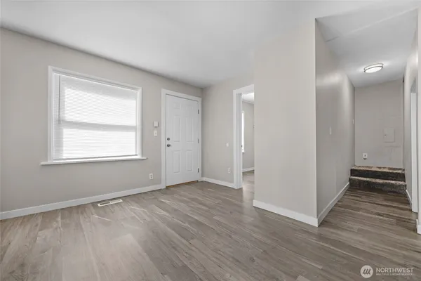 a view of an empty room with wooden floor and a window