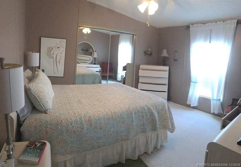 16152 Southwest Five Wood Way Indiantown, FL 34956 - Photo 5 of 9 a bedroom with a bed and a chandelier