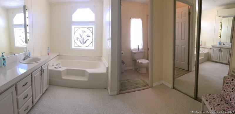 16152 Southwest Five Wood Way Indiantown, FL 34956 - Photo 9 of 9 a spacious bathroom with a bathtub a mirror a vanity and a shower