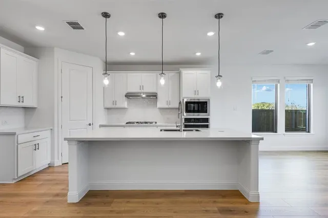 a large kitchen with kitchen island a sink stainless steel appliances and cabinets