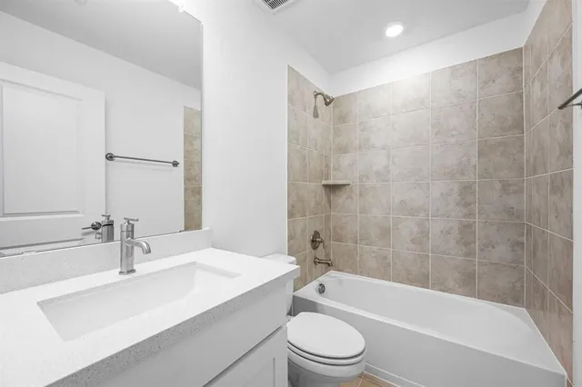 a bathroom with a bathtub shower sink mirror vanity and toilet