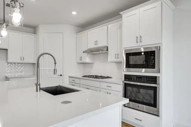 a kitchen with stainless steel appliances a stove a sink and a microwave