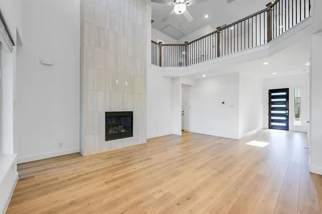 a view of an empty room with wooden floor and a fireplace
