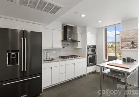 a kitchen with stainless steel appliances granite countertop a sink a stove and white cabinets