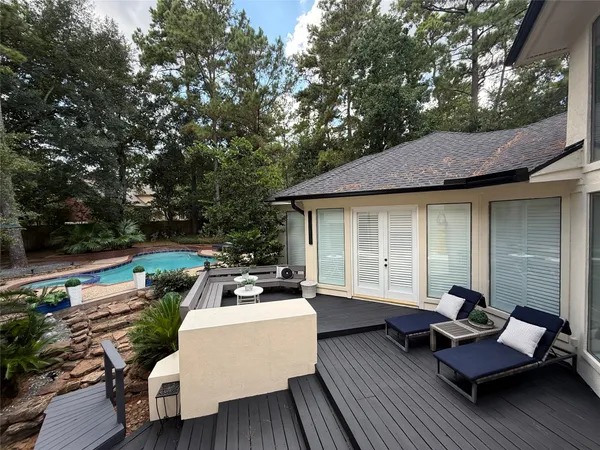 a view of a patio with couches table and chairs with wooden floor and fence