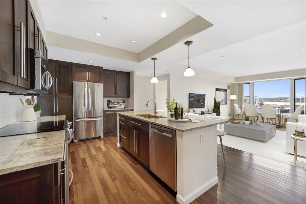 a kitchen with stainless steel appliances kitchen island granite countertop a stove refrigerator and cabinets