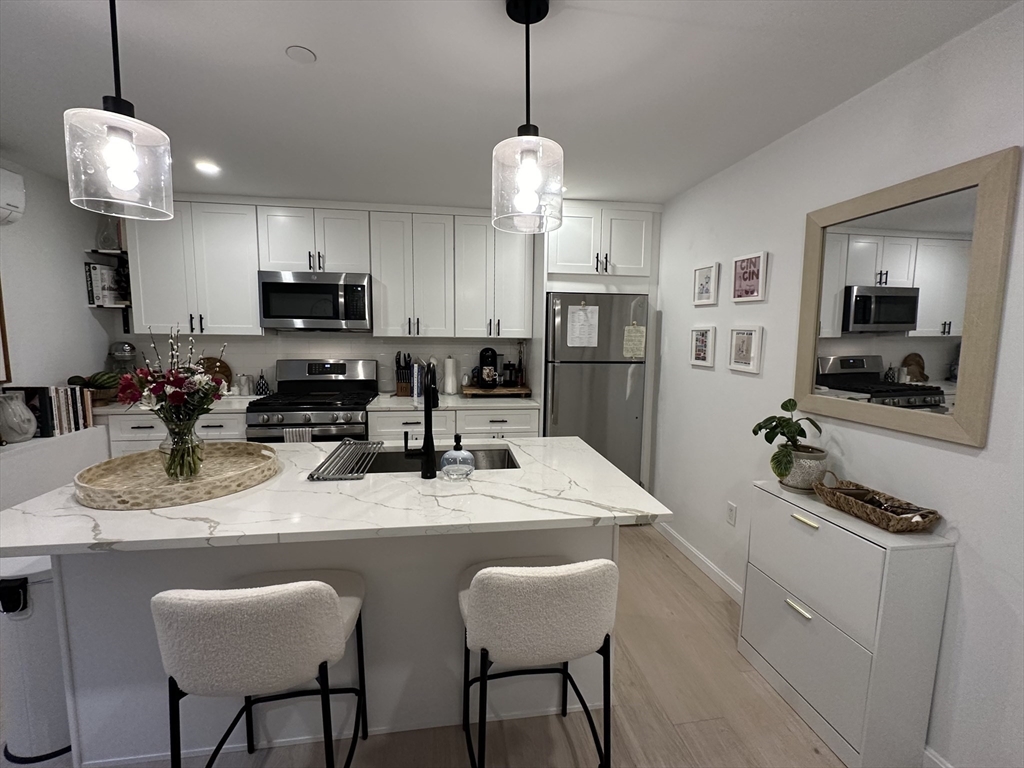 24 Ferrin Street, Unit 2 Boston, MA 02129 - Photo 1 of 9 a kitchen with stainless steel appliances granite countertop a sink a stove a refrigerator a kitchen island with chairs and cabinets