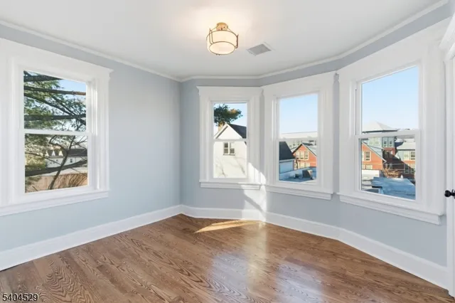 a view of an empty room with window and wooden floor