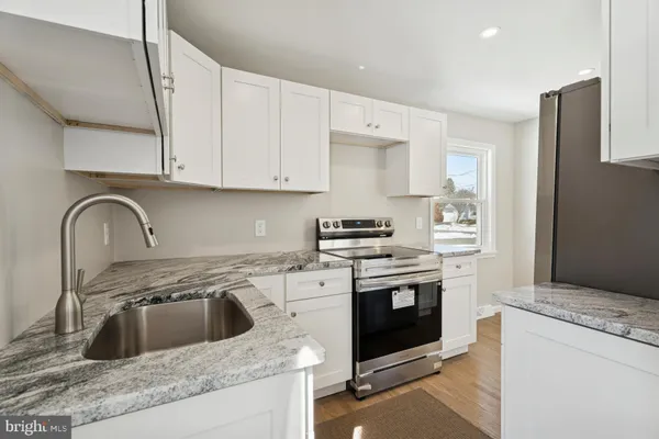 a kitchen with granite countertop a stove sink and cabinets