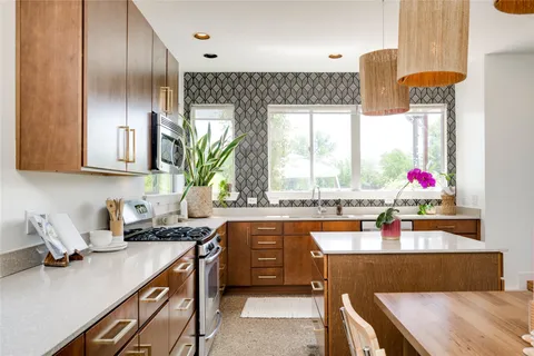 a kitchen with granite countertop a stove a sink and a wooden cabinets