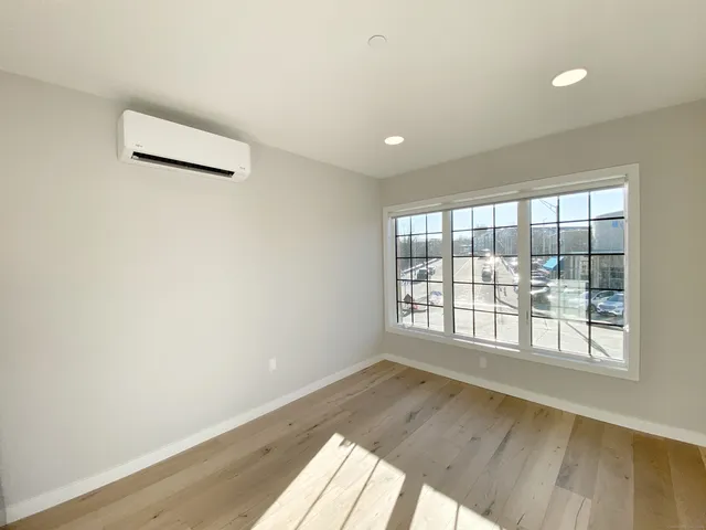 an empty room with wooden floor and windows