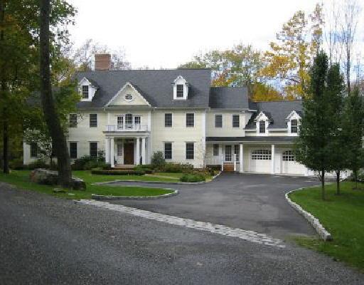 a view of house with a big yard and large trees